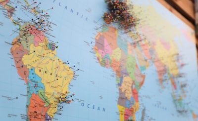 A close-up of a world map with colorful pins marking various locations.