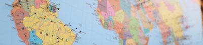A close-up of a world map with colorful pins marking various locations.