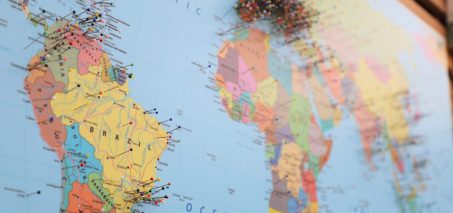 A close-up of a world map with colorful pins marking various locations.