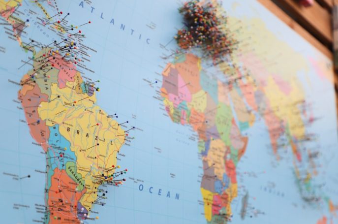 A close-up of a world map with colorful pins marking various locations.