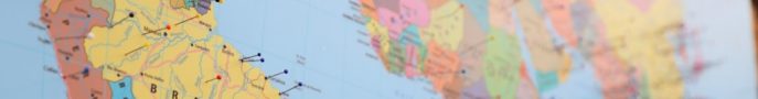 A close-up of a world map with colorful pins marking various locations.