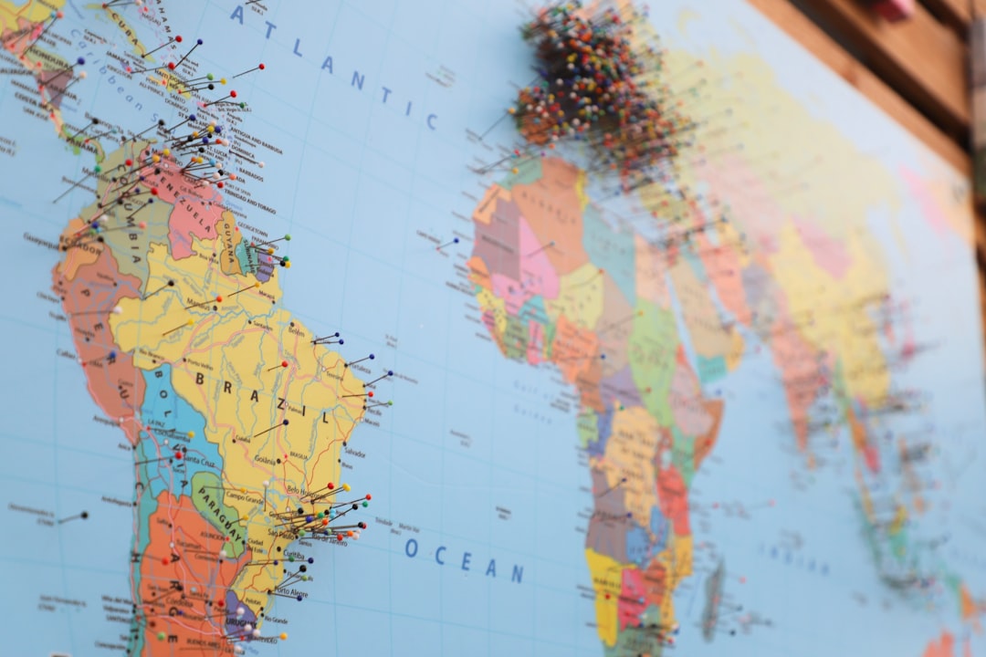 A close-up of a world map with colorful pins marking various locations.