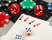 Close-up of playing cards, poker chips, and dice on a laptop keyboard.